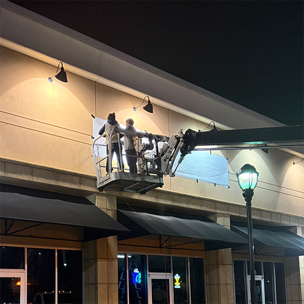 Channel letter sign installation Metro Atlanta by Signs & More technicians on lift installing illuminated building signage at night